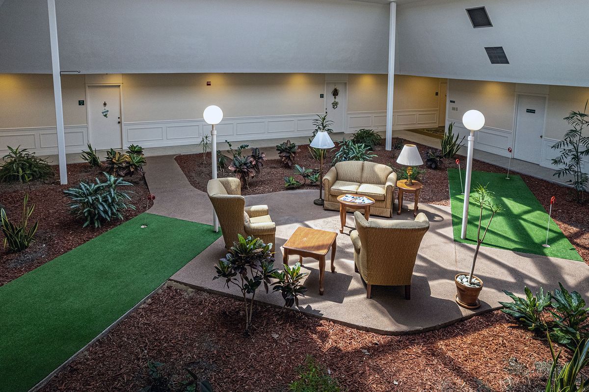 A cozy seating arrangement with armchairs and sofas in an indoor garden setting, featuring plants and decorative lamps.