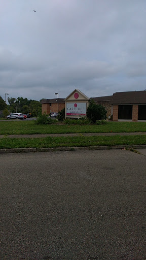 A view of a building with a sign and a parking lot under a cloudy sky.