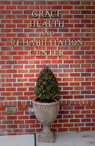 A welcoming entrance to a health and rehabilitation center with a brick wall and decorative plant.