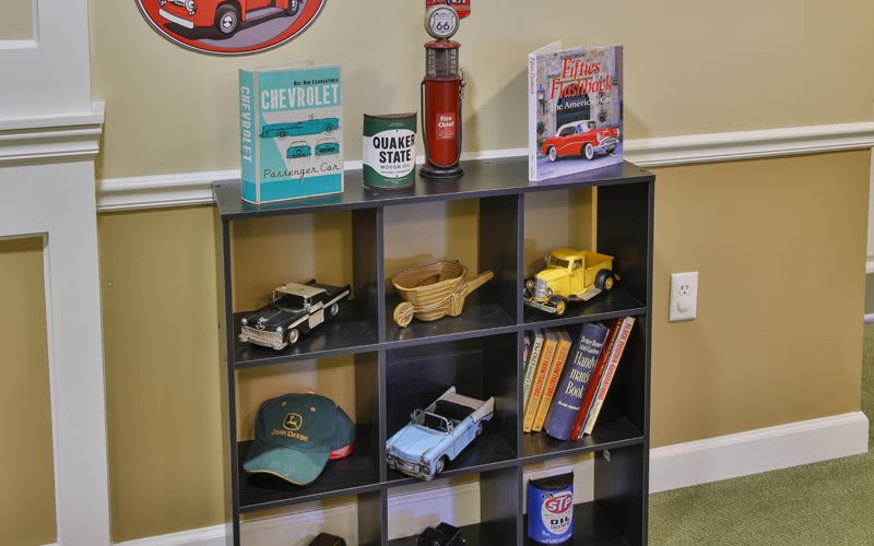 A decorated shelf featuring model cars, books, a cap, and various decor items displayed in storage cubes.