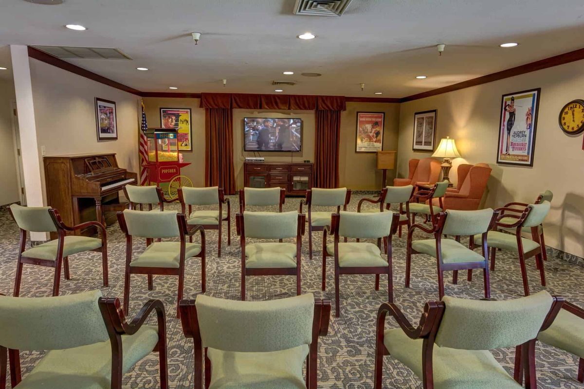 A well-arranged conference room featuring neatly aligned chairs, artwork on the walls, and warm lighting.
