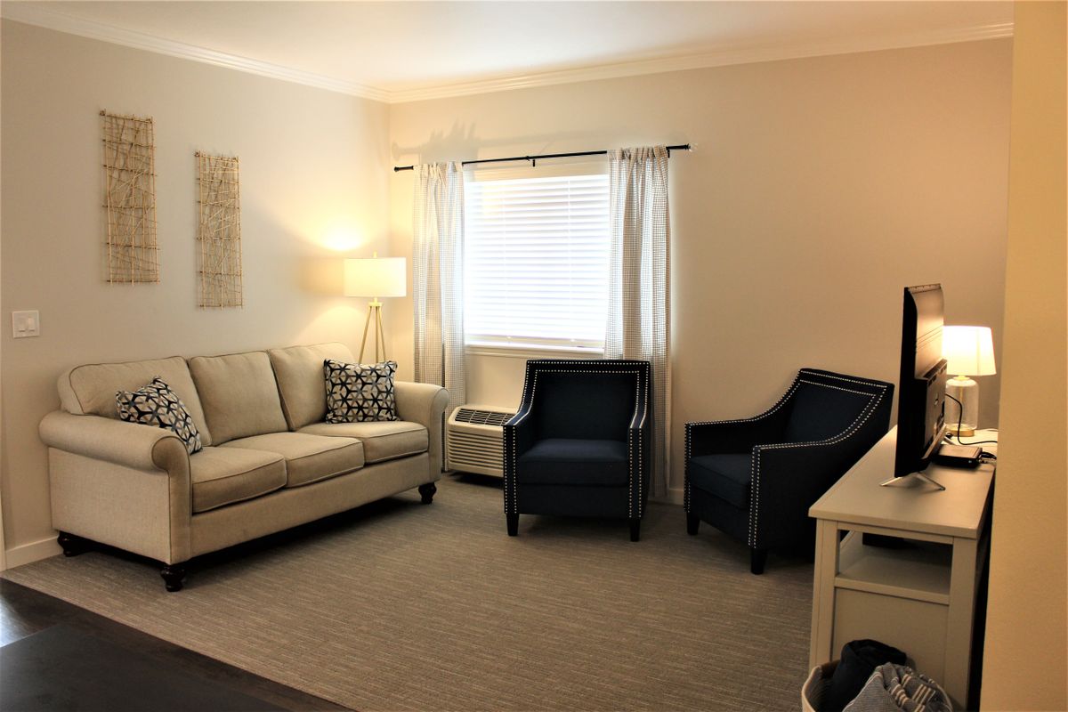A cozy living room with a sofa, chairs, and a floor lamp.