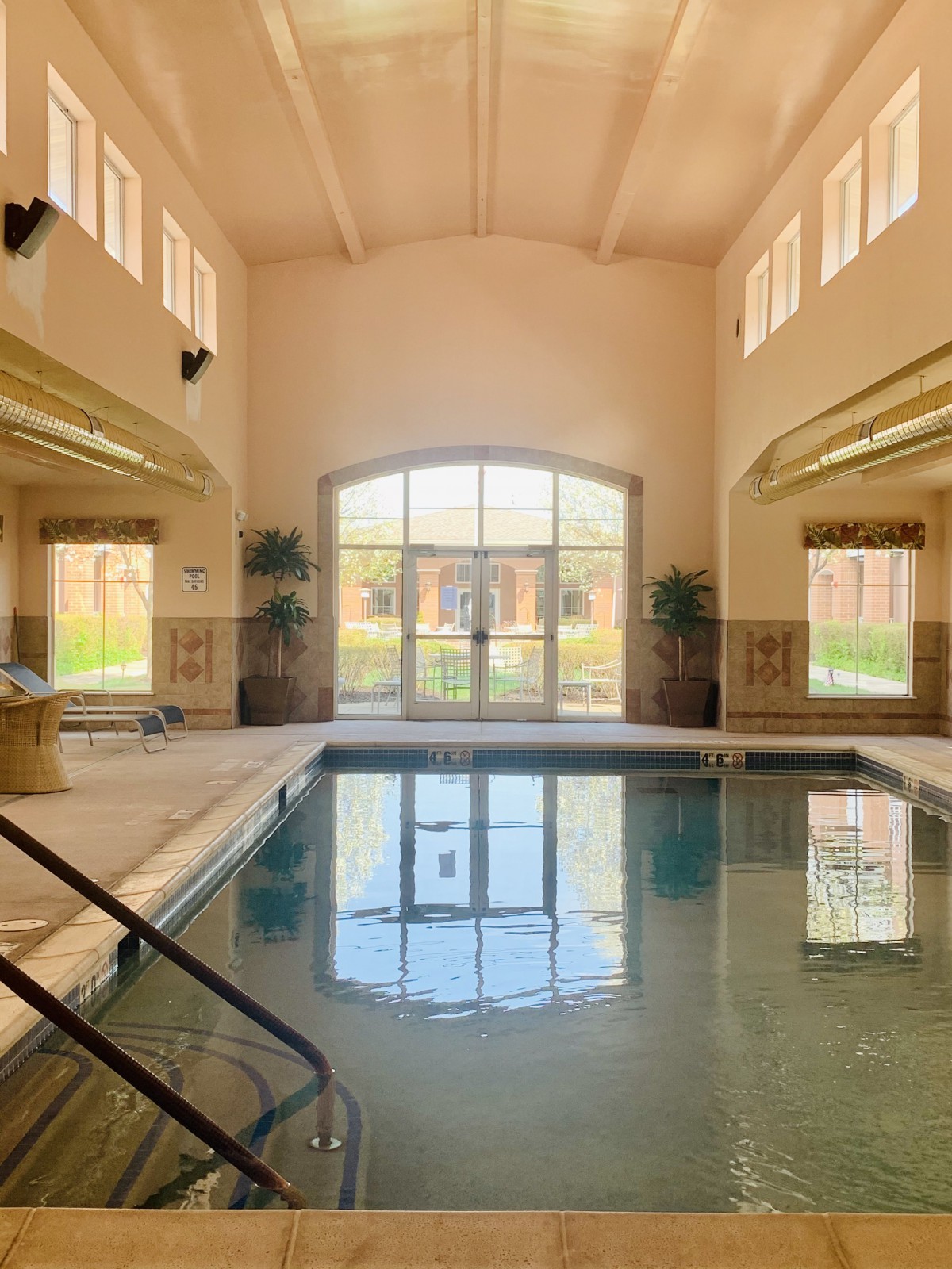 A tranquil indoor pool area with large windows letting in natural sunlight.