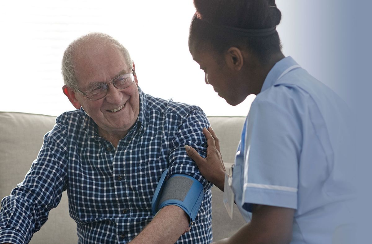 A nurse checks the blood pressure of an elderly patient in a healthcare setting.