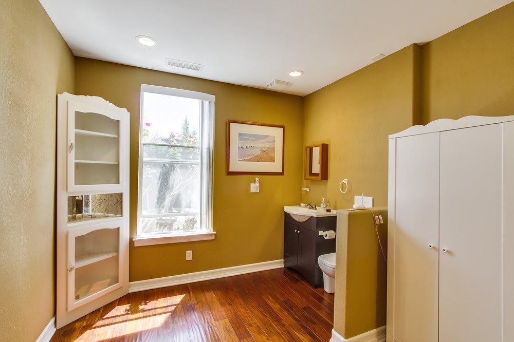 A cozy bathroom with wooden floors, featuring a sink, toilet, and built-in shelves.