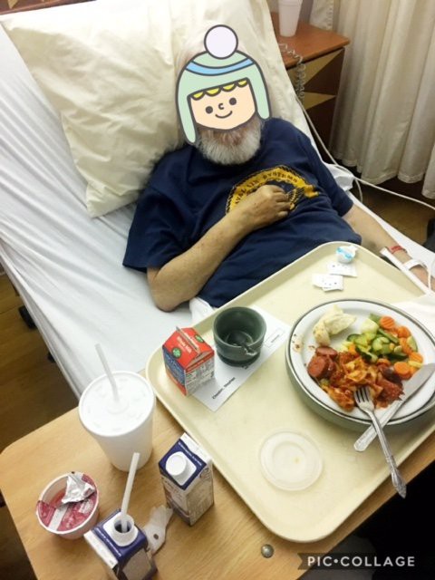 A patient in a hospital bed with a meal tray in front of them.