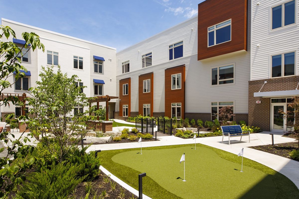 A modern residential building with a landscaped courtyard and putting green.