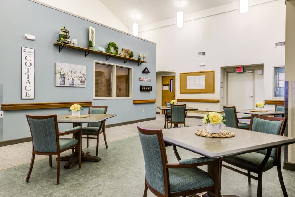 A cozy dining area with neatly arranged tables and chairs, decorated walls, and soft lighting.
