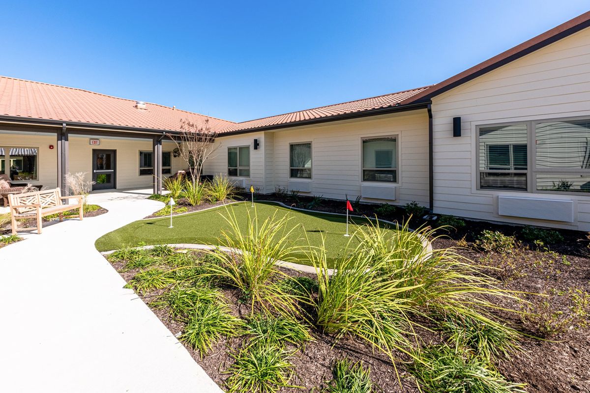 A modern building with a landscaped yard under a clear blue sky.