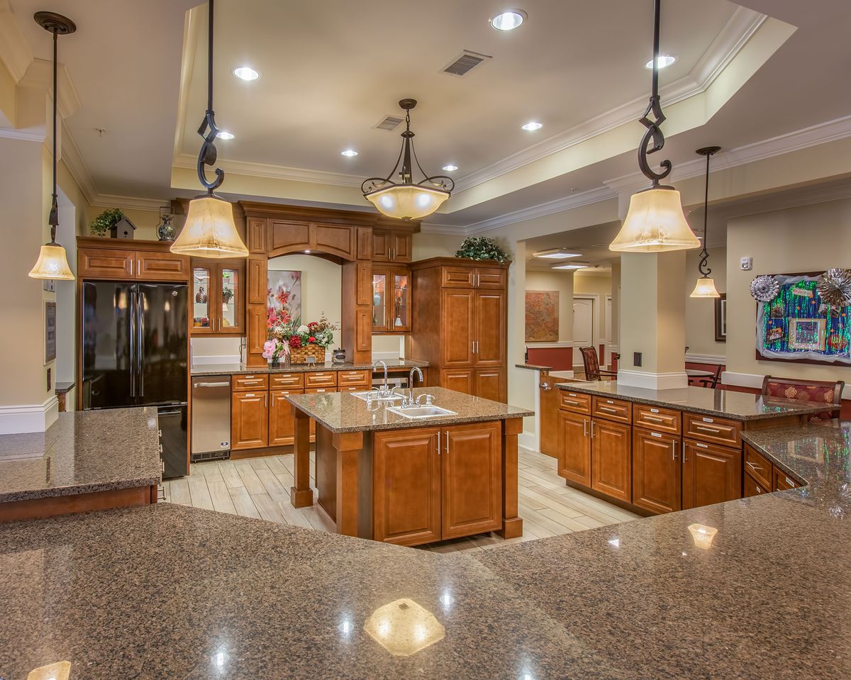A spacious, modern kitchen featuring wood cabinetry, a central island, and elegant pendant lighting.