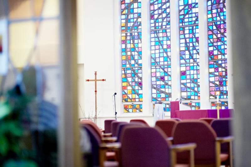 Interior view of a church with stained glass windows and seating.