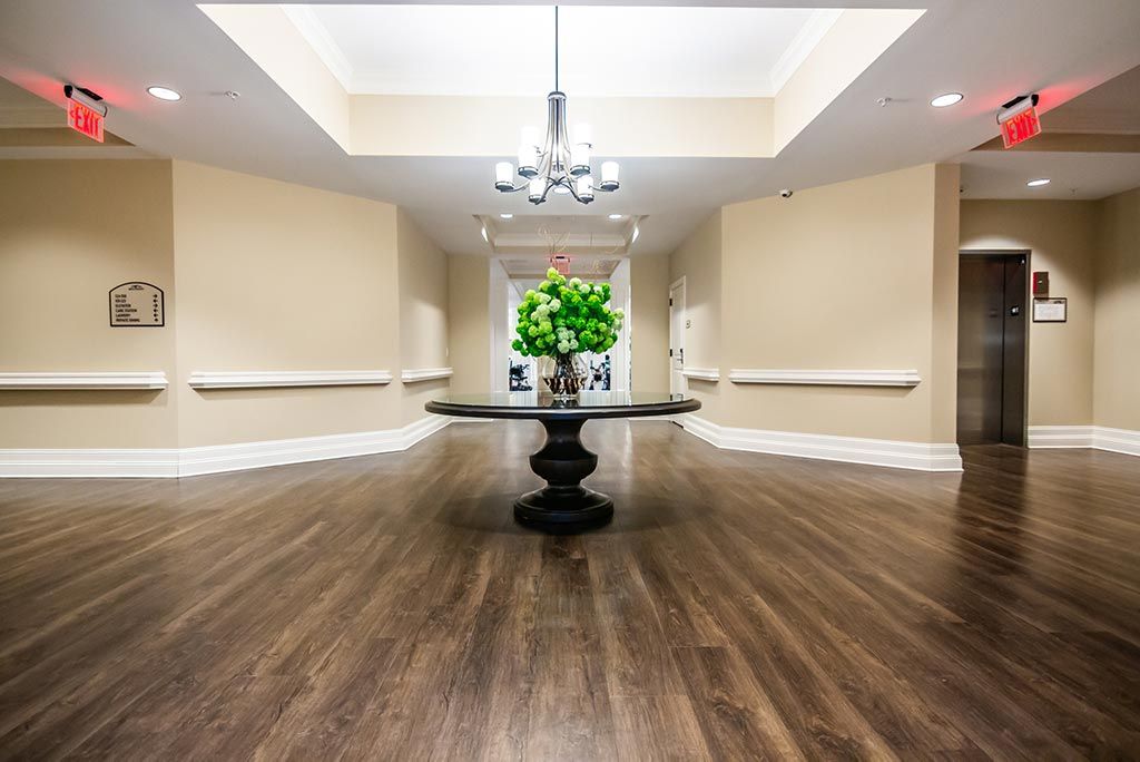 A spacious lobby area with a central table adorned with flowers and a hanging chandelier.