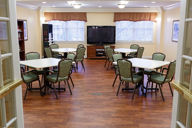 A neatly arranged meeting room with tables, chairs, and a television.
