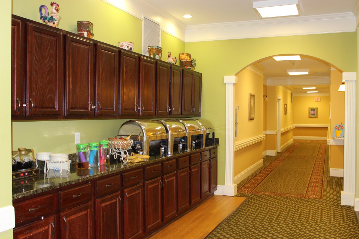 A buffet setup with various food containers and drinks in a well-lit hallway.