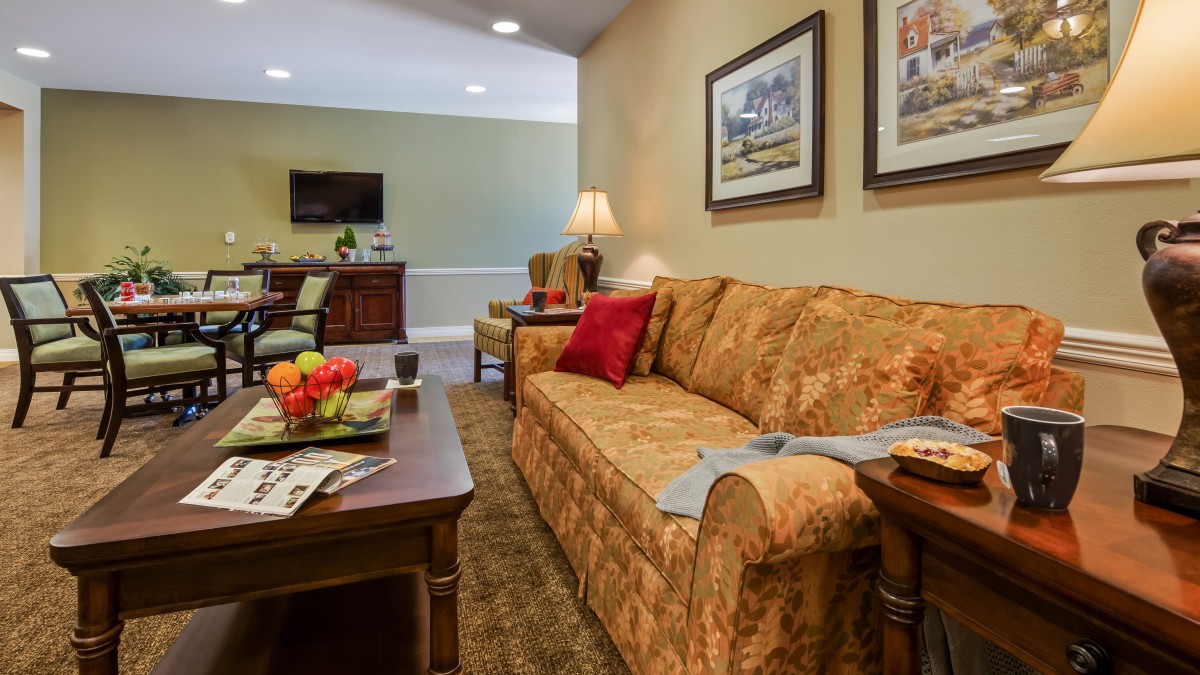 Cozy living room with a patterned sofa, wooden coffee table, and framed artwork on the walls.