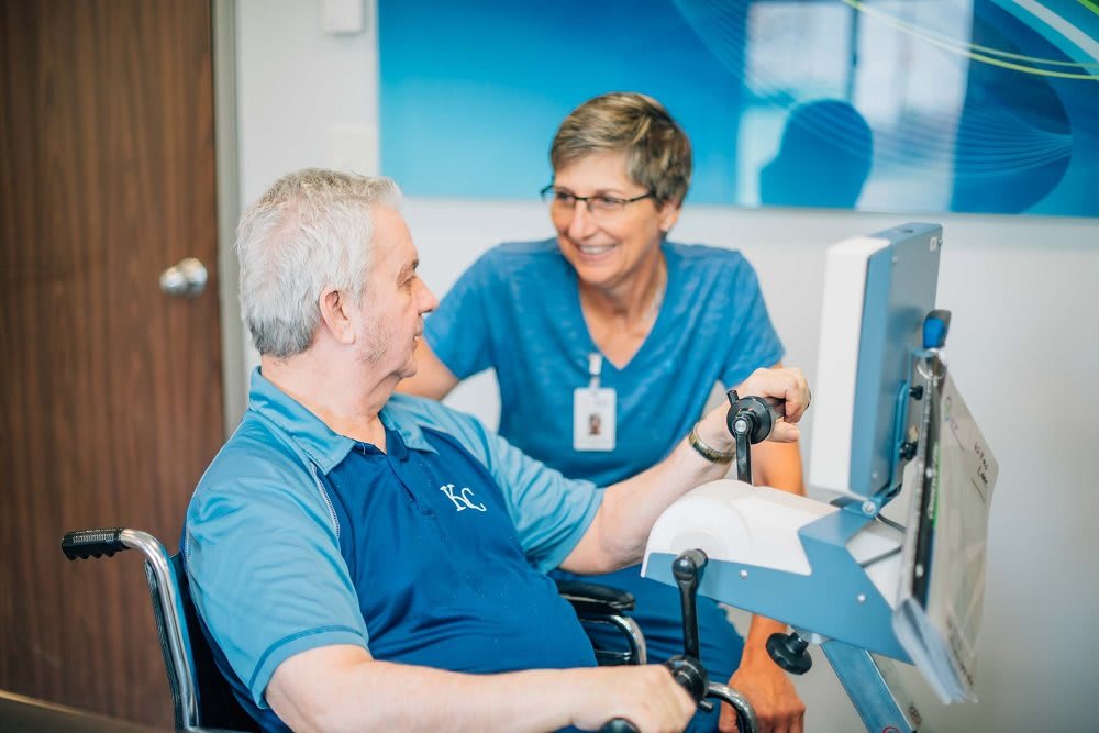 A healthcare professional assists a patient with rehabilitation exercises in a clinical setting.