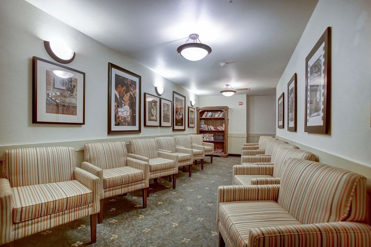 Empty waiting room with striped chairs and framed artwork on the walls.