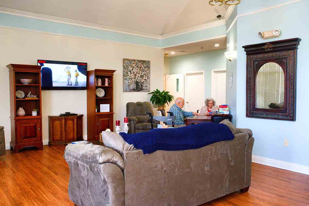 A cozy living room with two people sitting on a sofa, watching television.