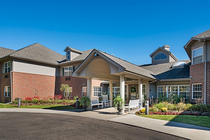 Modern residential building with a landscaped entrance under a clear blue sky.