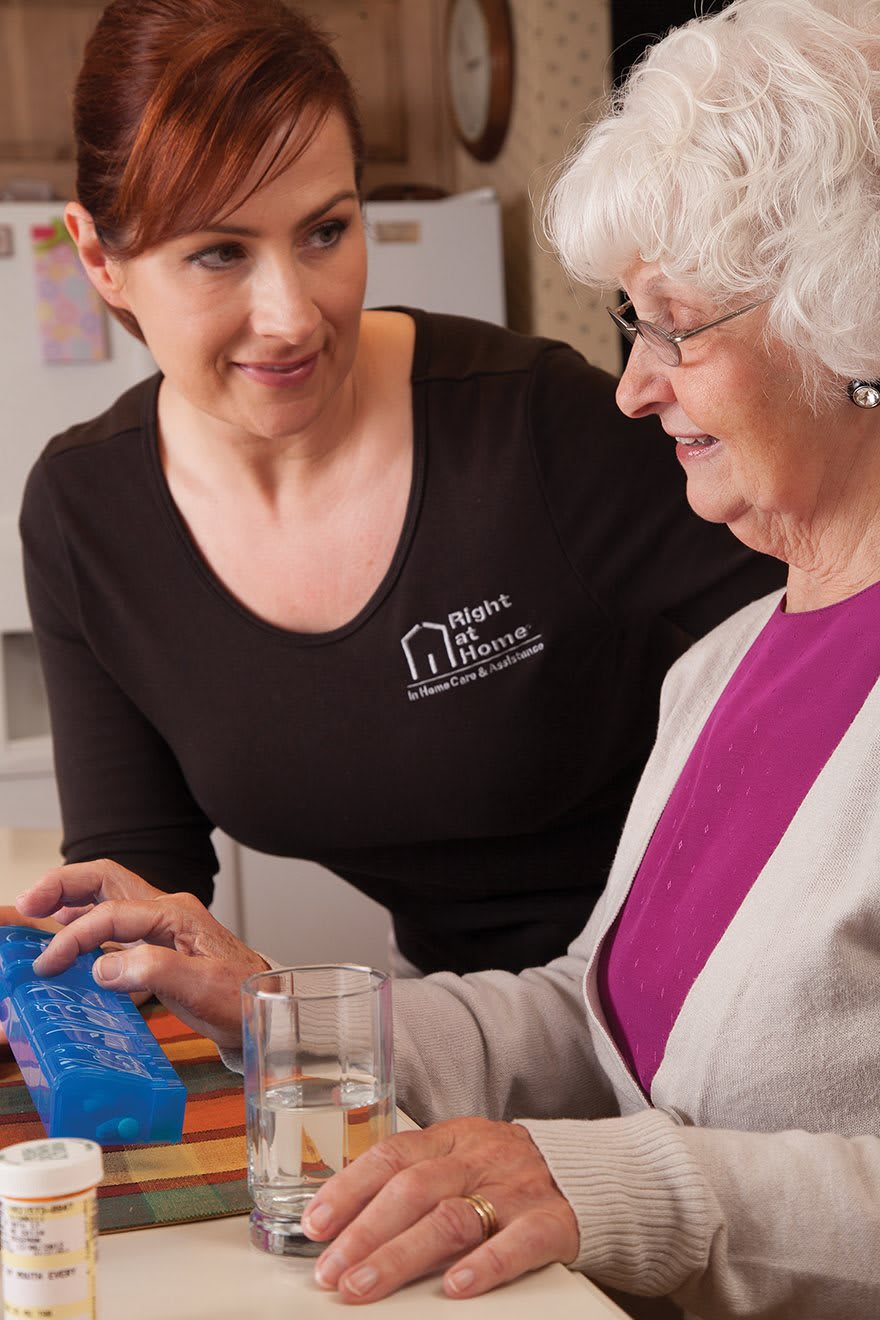 A caregiver assisting an elderly woman with her medication at home.