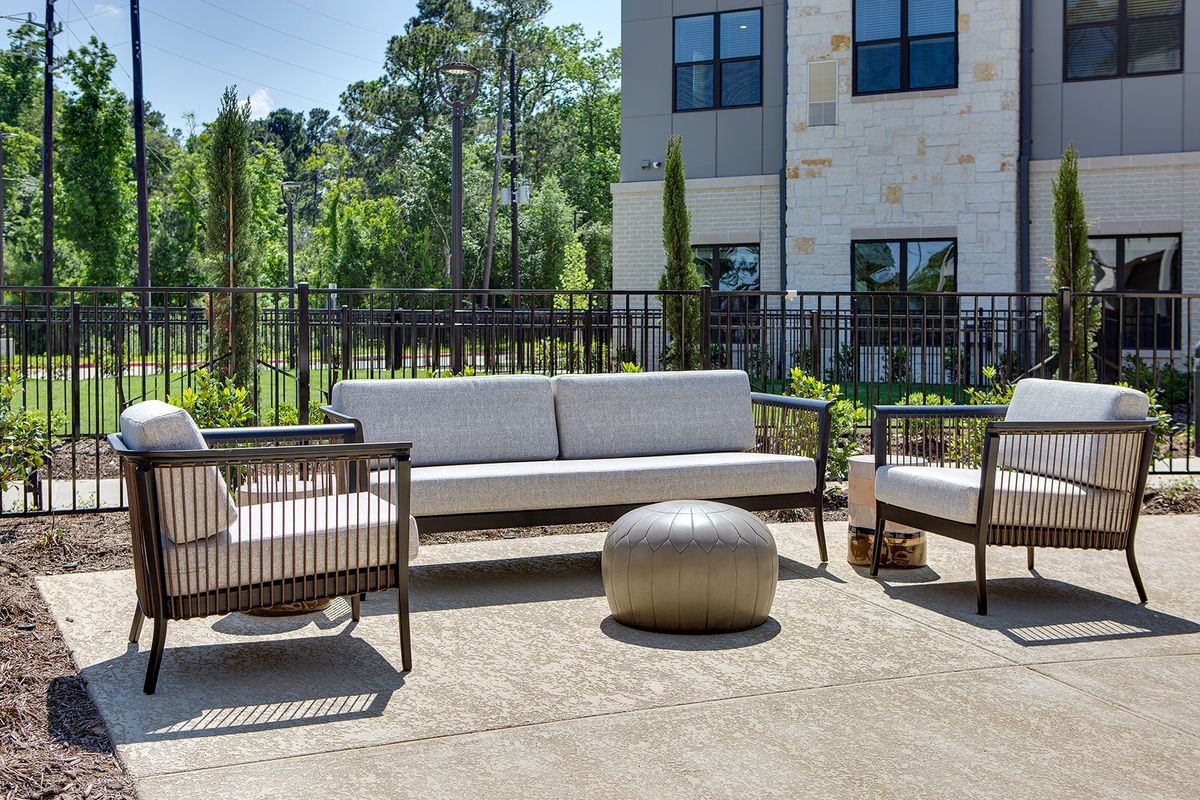 A modern outdoor seating area with a sofa, chairs, and a small round table.