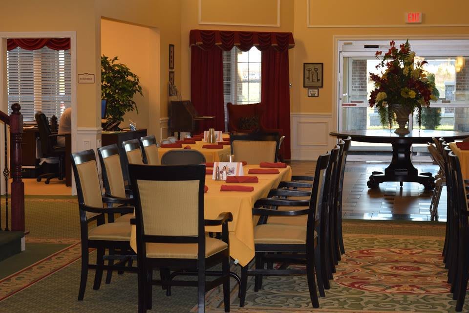 A well-arranged dining area with a large table and several chairs, featuring elegant decor and greenery.