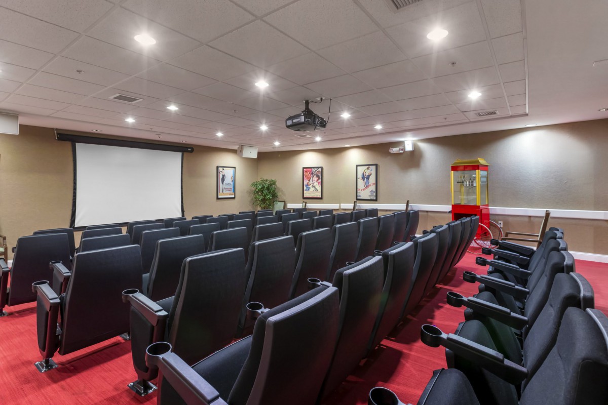 A small theater room with rows of comfortable chairs and a large screen, ready for a screening.