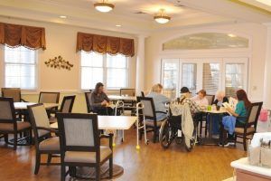 A cozy dining area in a nursing home where residents are gathered around tables.