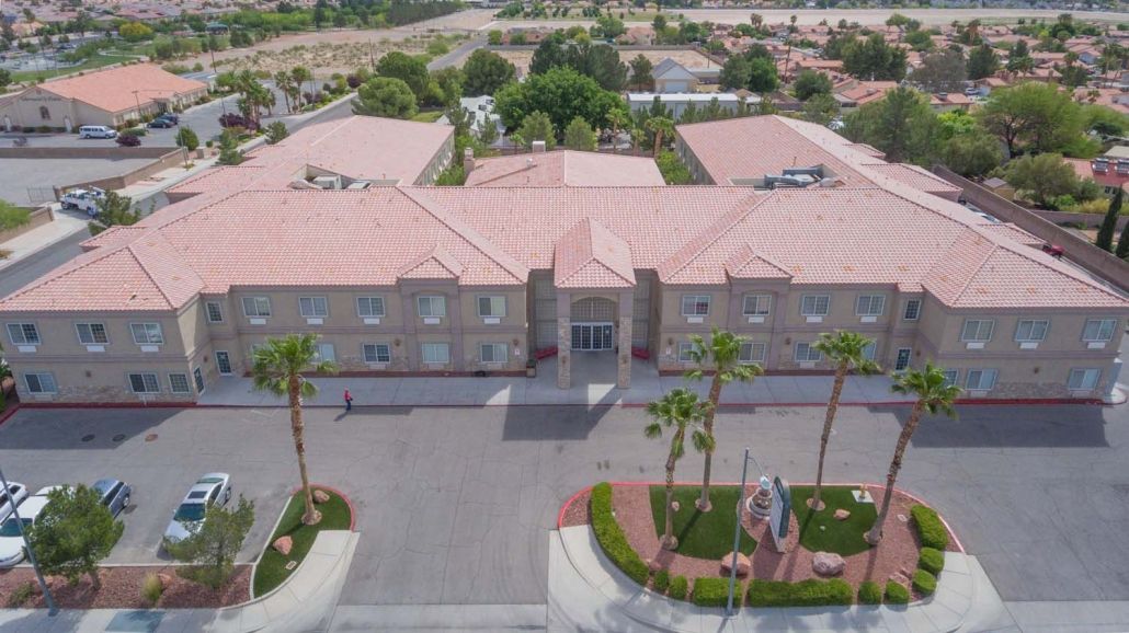 An aerial view of a large building complex with palm trees and a parking lot.