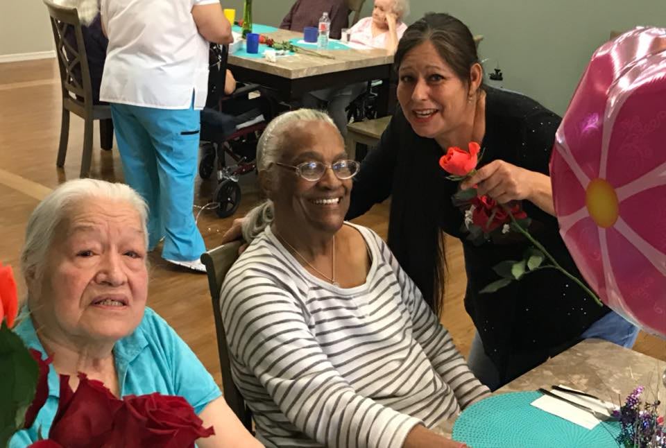 A joyful moment in a care home with elderly women receiving flowers.