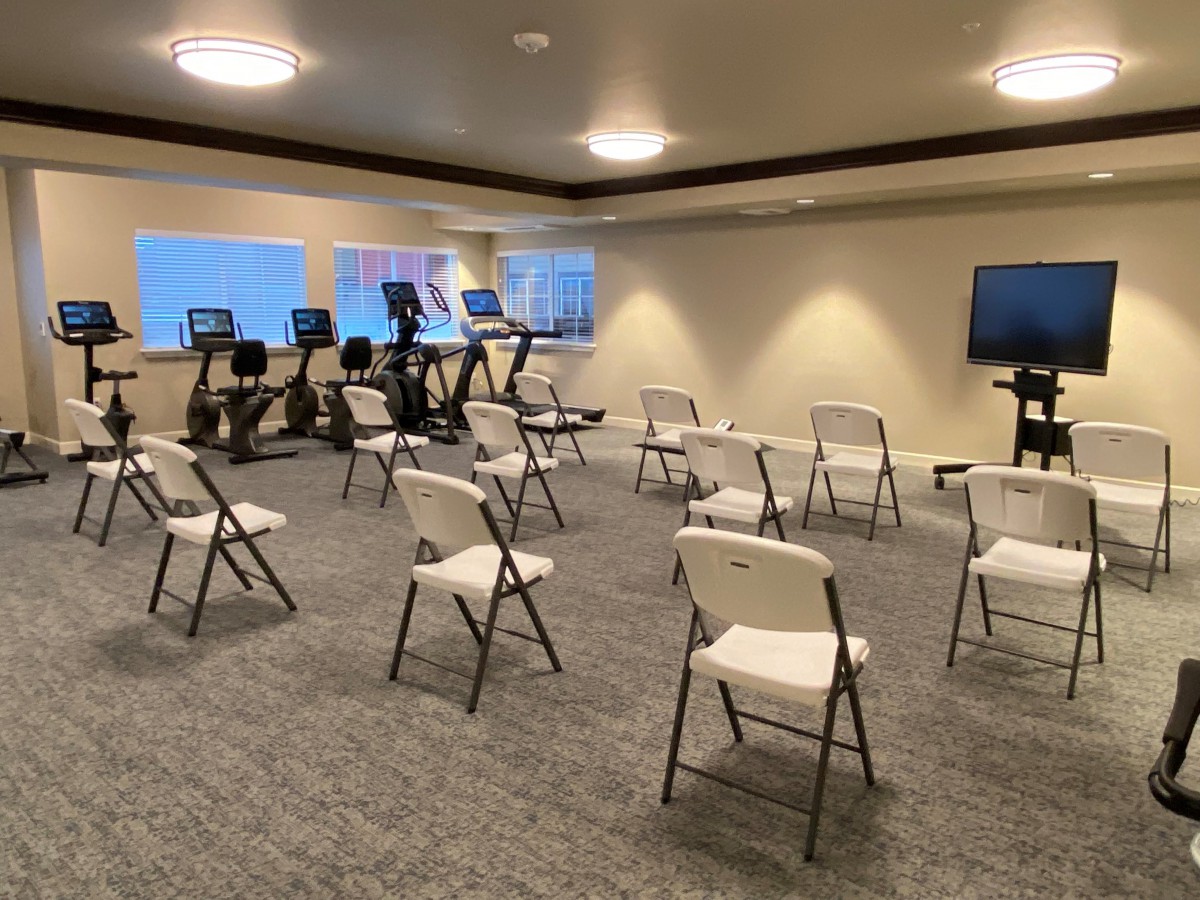 A hybrid space featuring exercise equipment and a seminar-style seating arrangement.