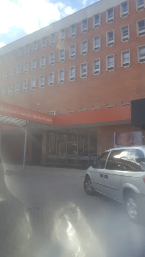 A view of an urban building with a vehicle parked nearby.