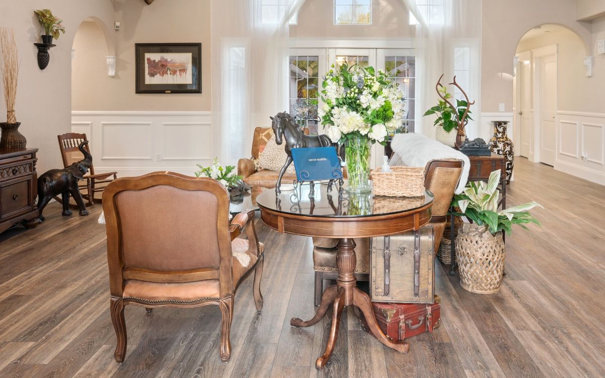 A cozy living room with antique furniture and vibrant floral arrangements.