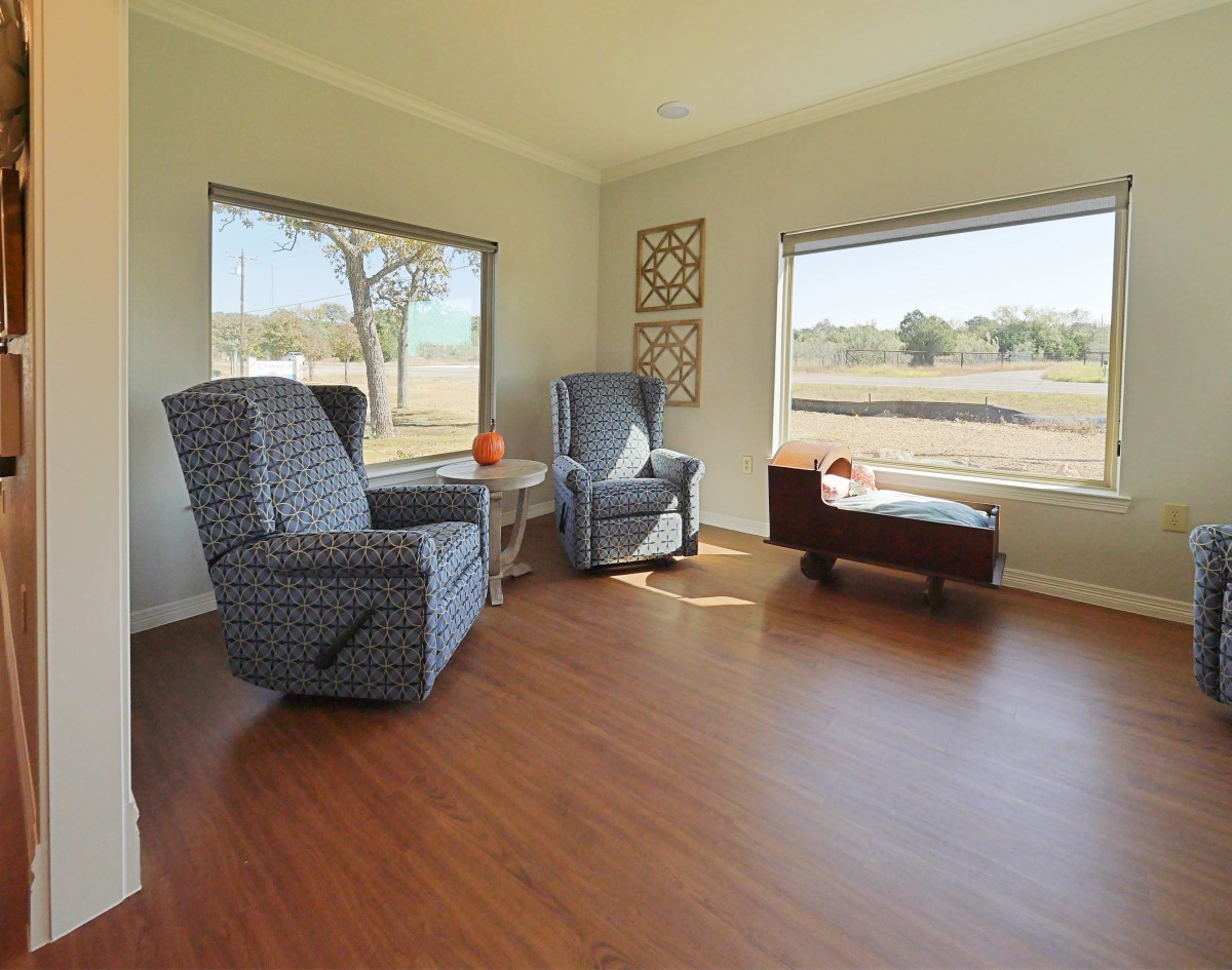 A cozy living room with armchairs and large windows overlooking a scenic outdoor view.