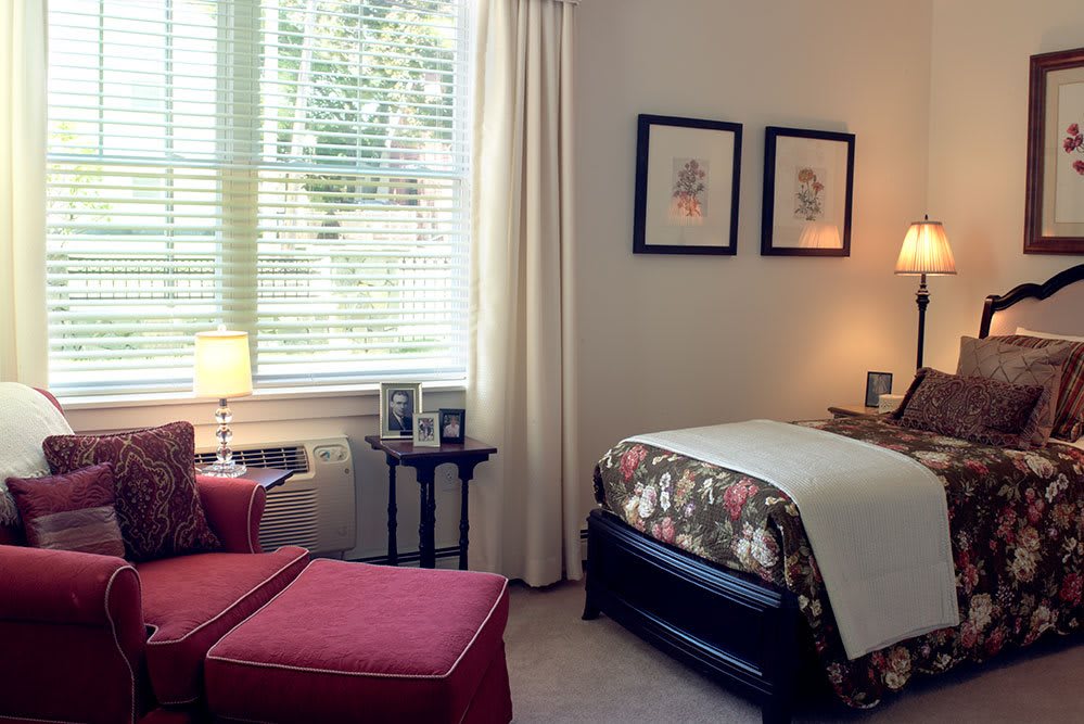 A cozy bedroom with a single bed, artwork on the wall, and a comfortable chair by the window.