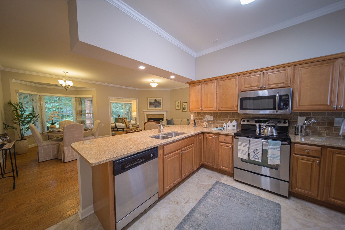 A modern kitchen with wood cabinets and stainless steel appliances in an open-concept layout.