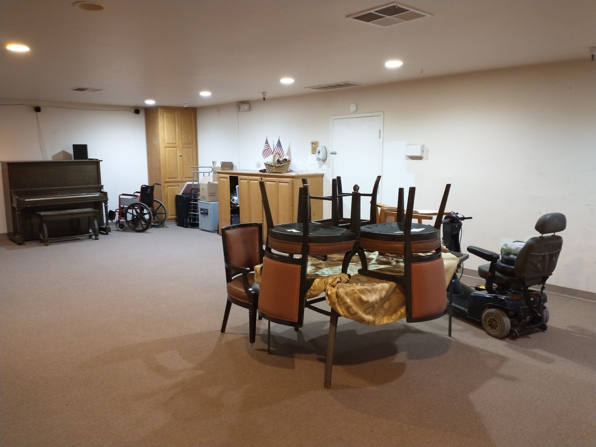 A room with stacked chairs on a table and various items in storage.