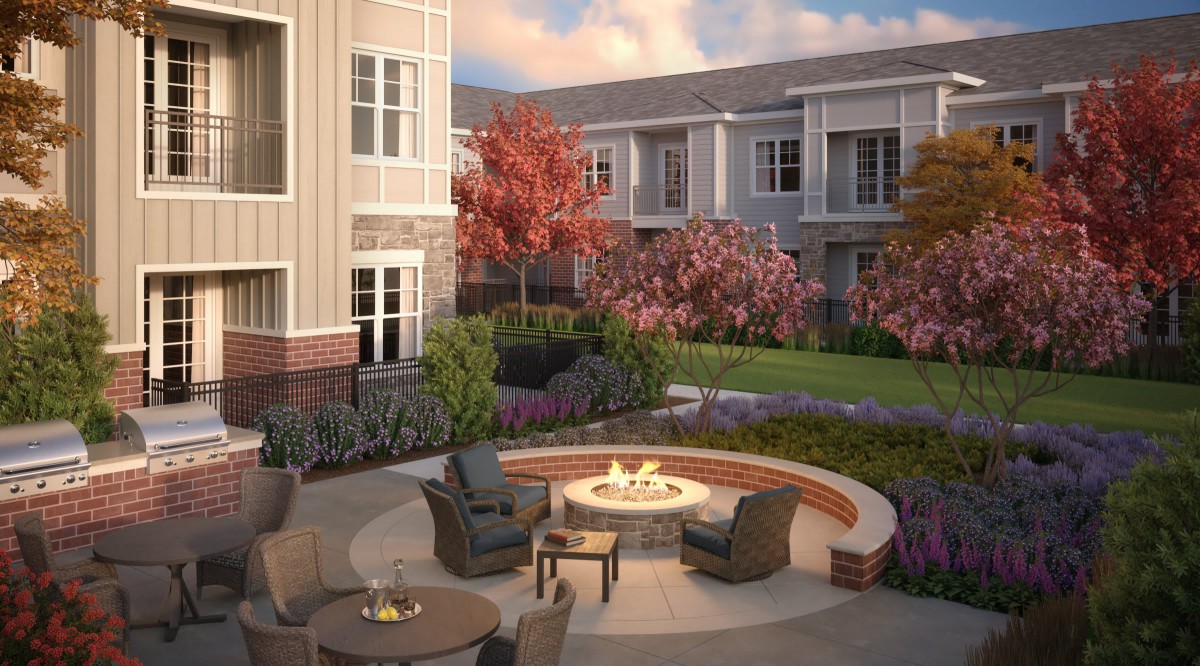 A cozy outdoor courtyard with a fire pit and seating area surrounded by landscaped greenery.