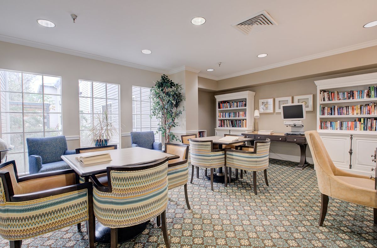 A well-lit study room with comfortable seating, bookshelves, and a computer workstation.