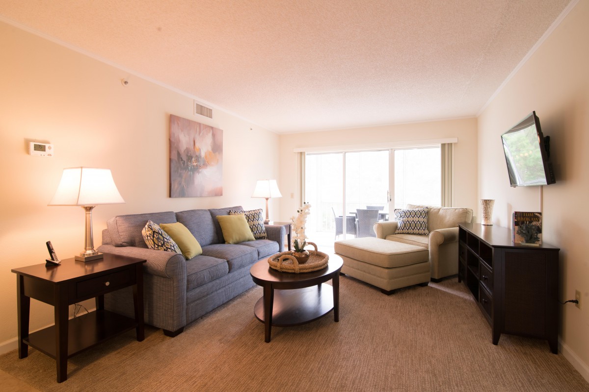 A cozy living room with a comfortable sofa and a coffee table, illuminated by warm lighting.