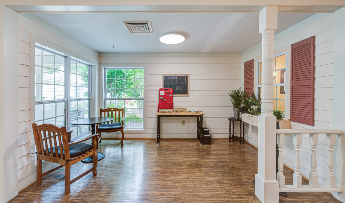 A cozy waiting area with wooden flooring, benches, and large windows allowing natural light.