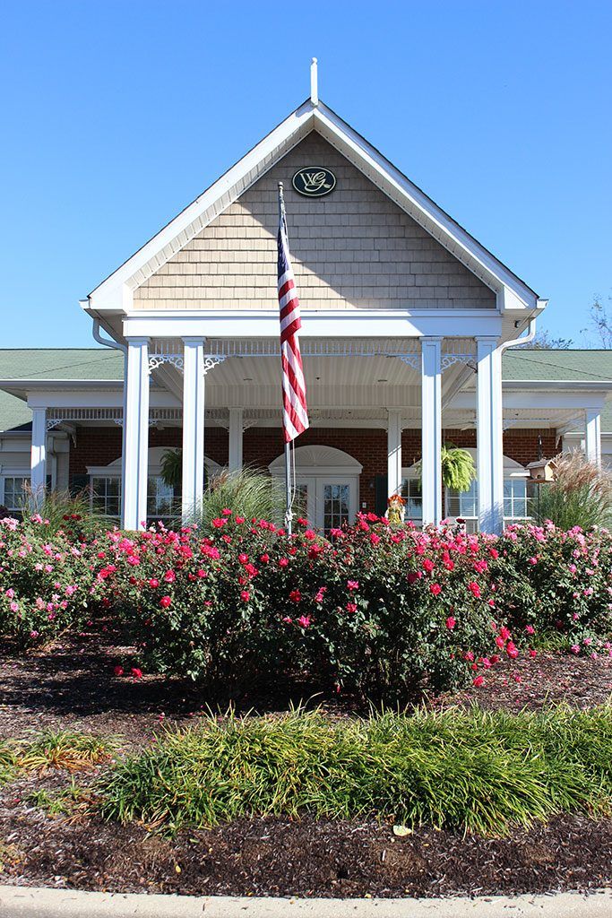 A well-landscaped entrance of a building with a flag and vibrant flower garden.