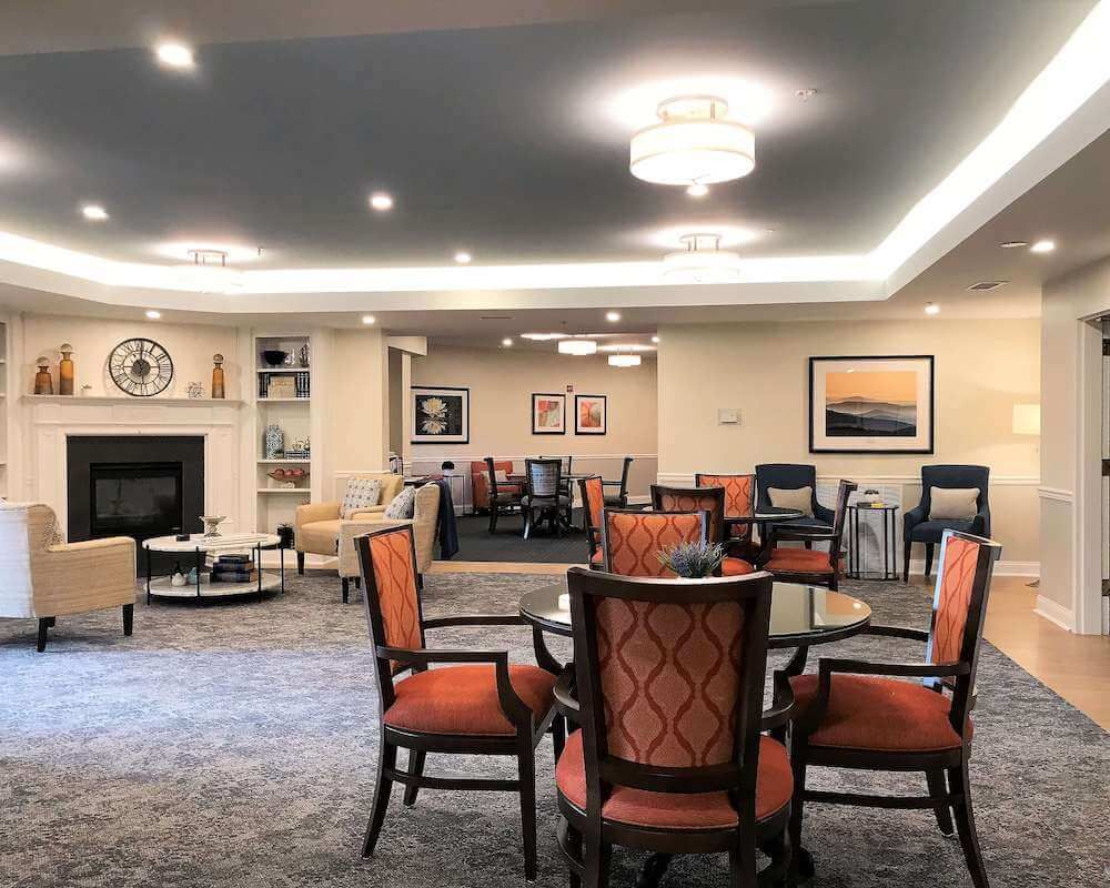 A cozy interior seating area with dining tables, chairs, a fireplace, and artwork on the walls.