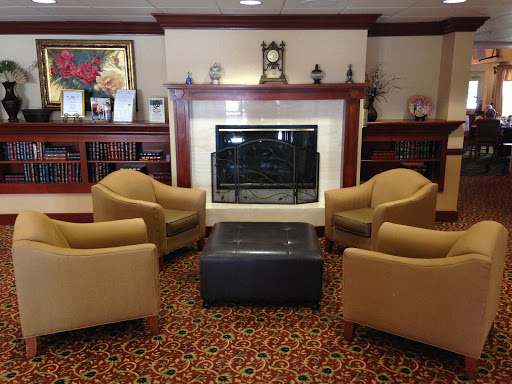A cozy seating area featuring two chairs and an ottoman arranged around a fireplace.
