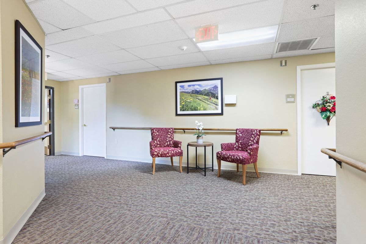 A hallway with two patterned chairs and a small table beneath a framed painting.