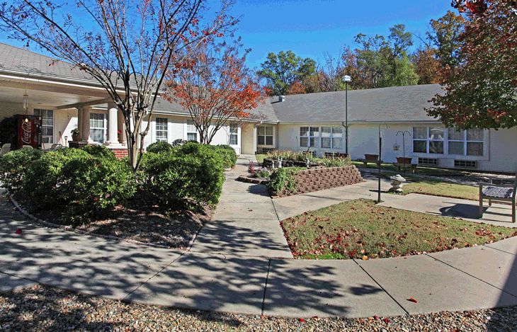 A residential building surrounded by a landscaped garden with walkways and trees.