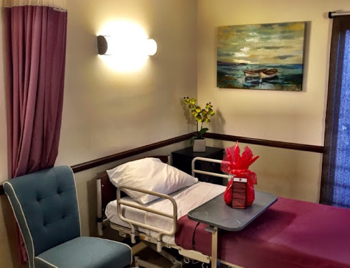 A cozy patient room featuring a hospital bed, a comfortable chair, and decorative elements.