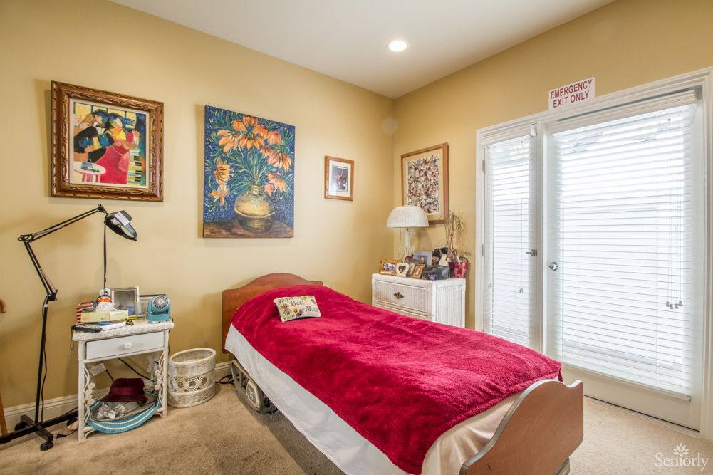 A cozy bedroom with a single bed and colorful artwork on the walls.