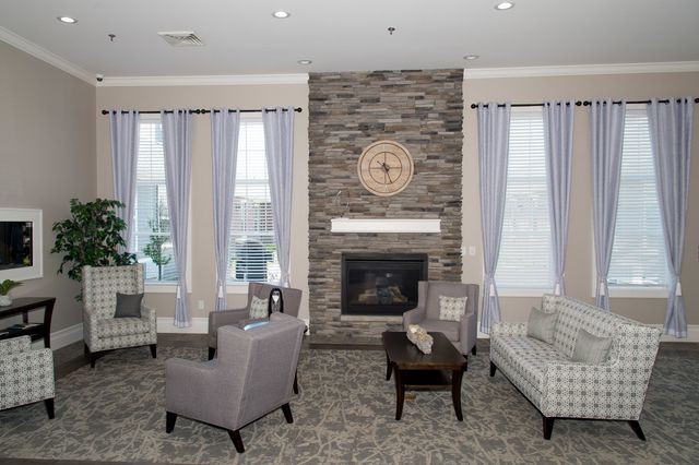 A modern living room with a stone fireplace, comfortable seating, and neutral decor.