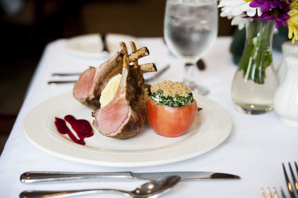 A beautifully presented rack of lamb with a vegetable accompaniment at a fine dining restaurant.